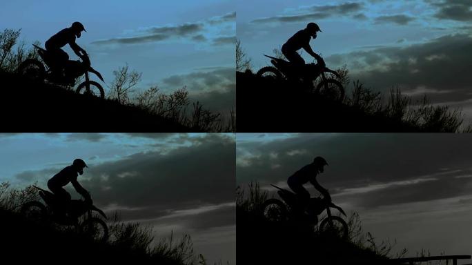 骑士在夜晚的剪影。他骑着极限摩托车下山
