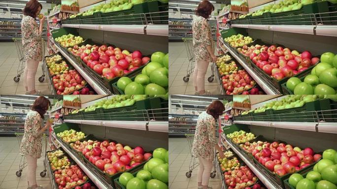 怀孕的女孩在杂货店闻到黄色的苹果