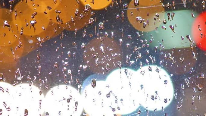 模糊背景。移动夜间交通的波克圈。在雨滴中透过玻璃散焦的夜间交通信号灯。彩色、模糊、bokeh灯光背景