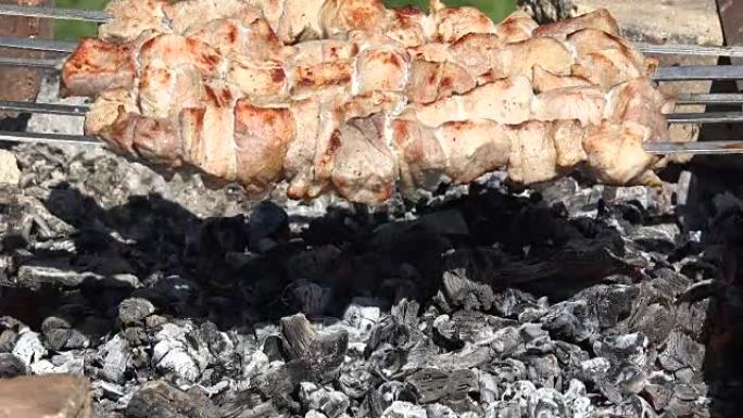 新鲜肉类的特写镜头在复古花园壁炉上的烟雾中烘烤在钢吐痰串上。
