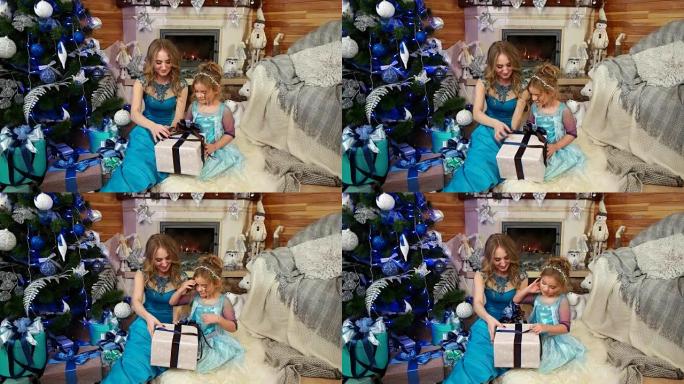 可爱的小女孩，有妈妈的样子，打开了一份圣诞礼物，精美地装在带蝴蝶结的包装纸盒里，圣诞树下有礼物，家人