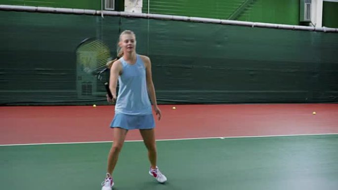 一名穿着运动服的少年在体育俱乐部练习网球比赛，女孩用球拍通过网打球