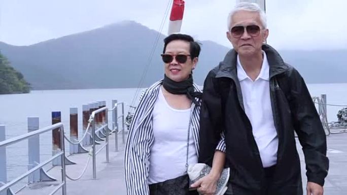 时尚的亚洲老年人一起在湖游轮码头散步。一起环游世界
