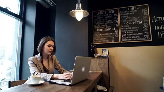 美丽的时髦女人在咖啡馆使用笔记本电脑