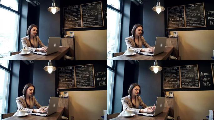 美丽的时髦女人在咖啡馆使用笔记本电脑
