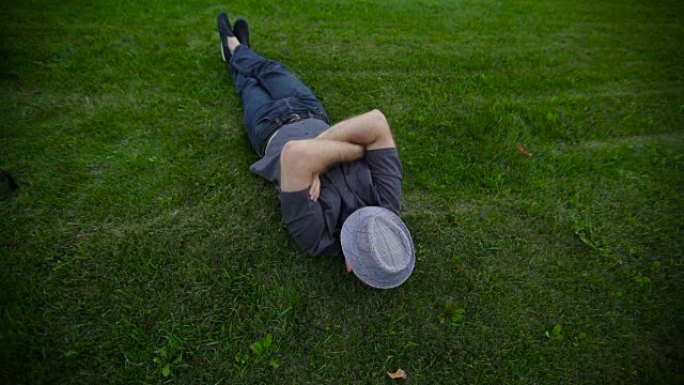 男人戴着帽子躺在公园的草地上