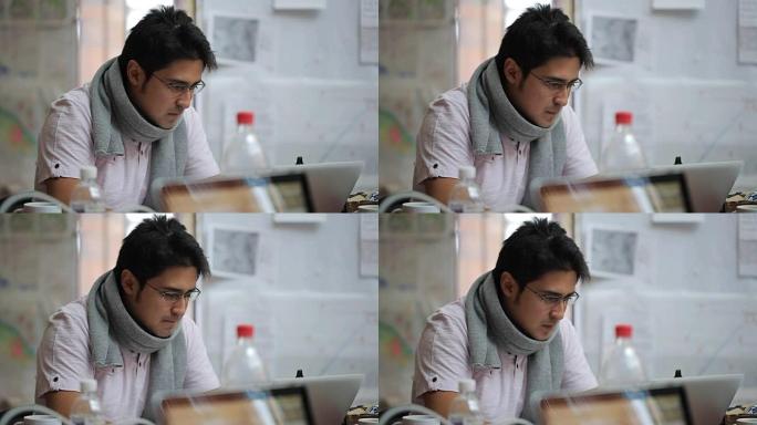 穿着眼镜和围巾在笔记本电脑上工作的亚洲外观制图师的男性