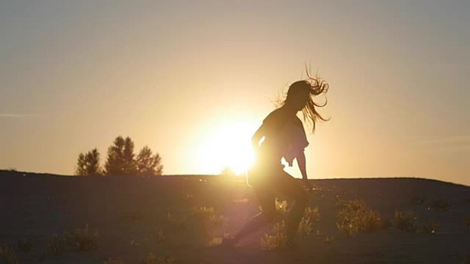 一个女孩专业舞者在日落时以慢动作跳跃的剪影