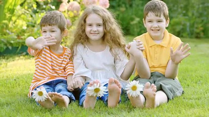 快乐的朋友在夏日公园的绿草丛中，带着雏菊花的孩子。