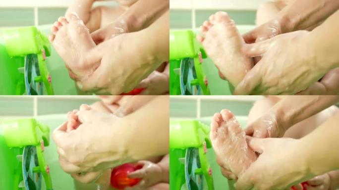 母亲洗脚诱人的婴儿肥皂。这个男孩微笑着玩五颜六色的玩具和水。孩子大约一年