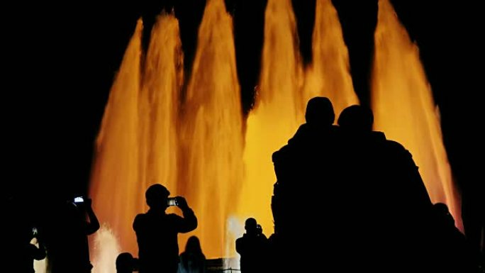 巴塞罗那歌唱喷泉中人们可辨认的轮廓。观看表演的人们，拍摄了喷泉