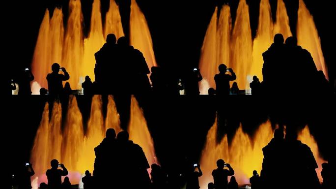 巴塞罗那歌唱喷泉中人们可辨认的轮廓。观看表演的人们，拍摄了喷泉