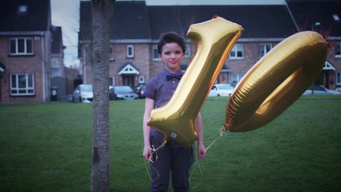 4k派对10岁生日男孩与气球在户外摆姿势