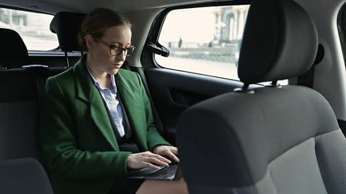 认真的女商人在笔记本电脑上的汽车上工作