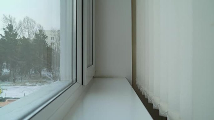 带有垂直百叶窗和外面飘落的雪的新窗户