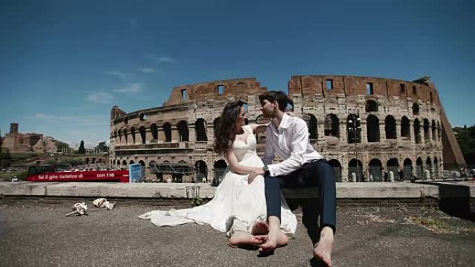 罗马体育馆的婚礼夫妇坐在旁边，彼此拥抱并热情地亲吻。意大利、欧洲的蜜月