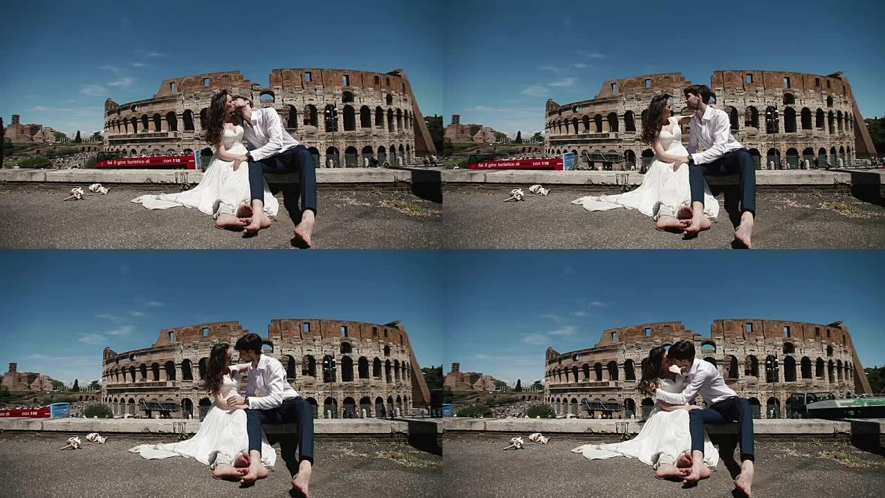 罗马体育馆的婚礼夫妇坐在旁边，彼此拥抱并热情地亲吻。意大利、欧洲的蜜月