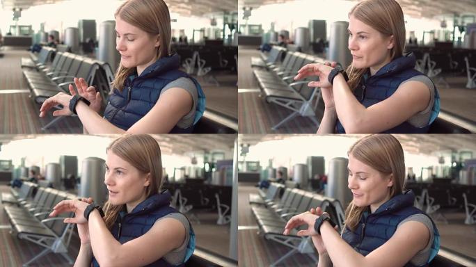 美丽迷人的年轻女子在机场使用智能手表。向朋友发送语音信息