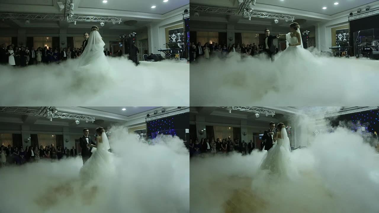 快乐的新婚夫妇跳舞华尔兹被白色烟雾笼罩。精彩的婚礼派对。