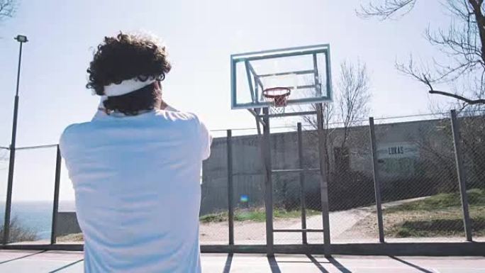 一名年轻的篮球运动员在室外球场打篮球时得分