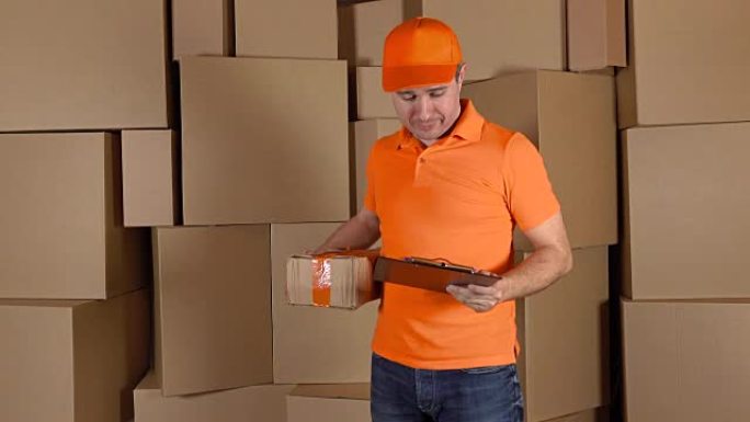 穿着橙色制服的人向客户运送严重损坏的包裹。棕色纸箱背景。不专业的工作和后悔的概念。全高清镜头