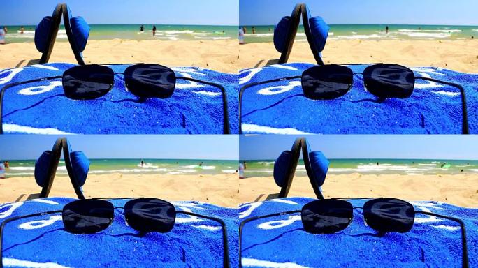 沙滩上的太阳镜和蓝色毛巾