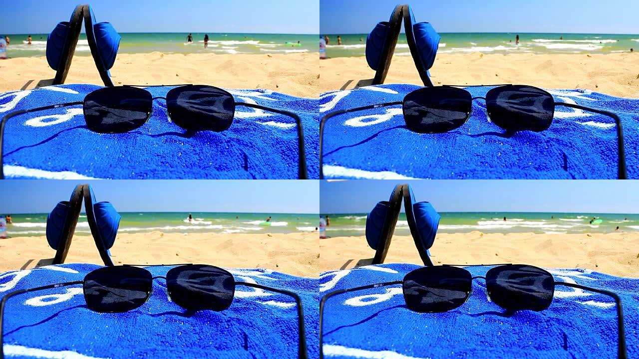 沙滩上的太阳镜和蓝色毛巾