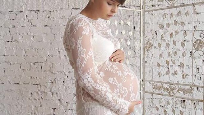 穿着裙子的美丽孕妇站在窗前。