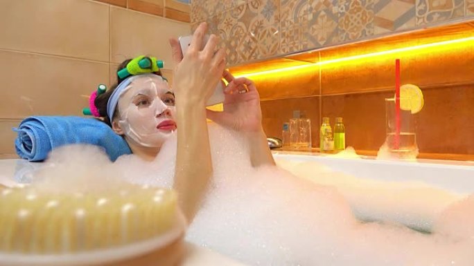 戴着口罩的黑发女人在泡沫浴缸里窃听智能手机。全高清视频