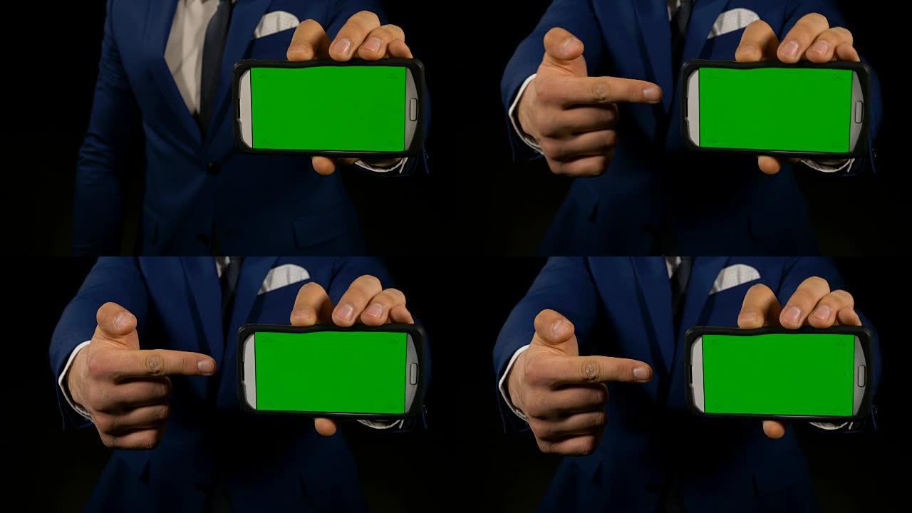 一名男子手持绿屏智能手机，用手指指着显示屏
