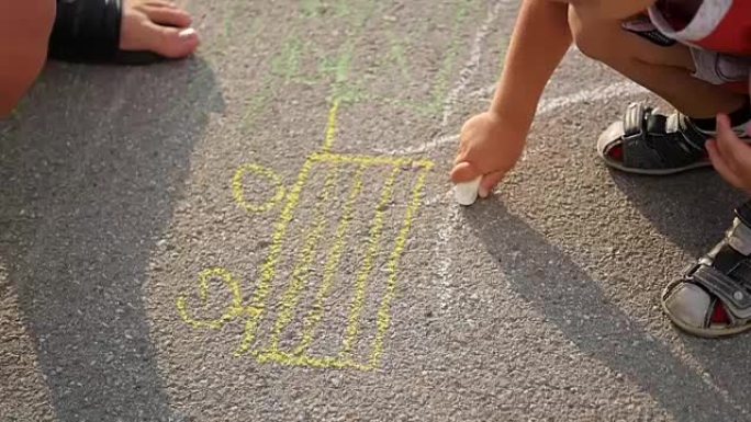 有孩子的家庭用粉笔在沥青上画画。户外游戏