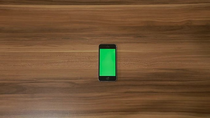 智能手机在木桌背景上放大手势。垂直
