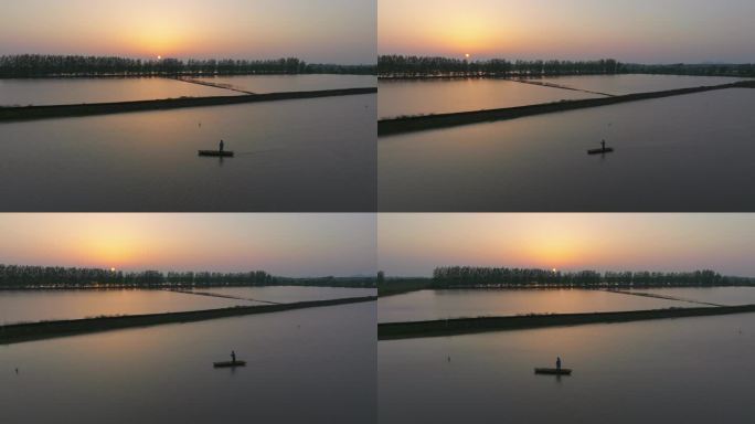 夕阳下渔村的鱼塘里渔民正划着小船风景航拍