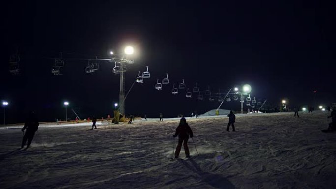 冬季夜间滑雪时地面举升机的操作。在滑雪胜地进行夜间滑雪和单板滑雪以及跑步滑雪缆车