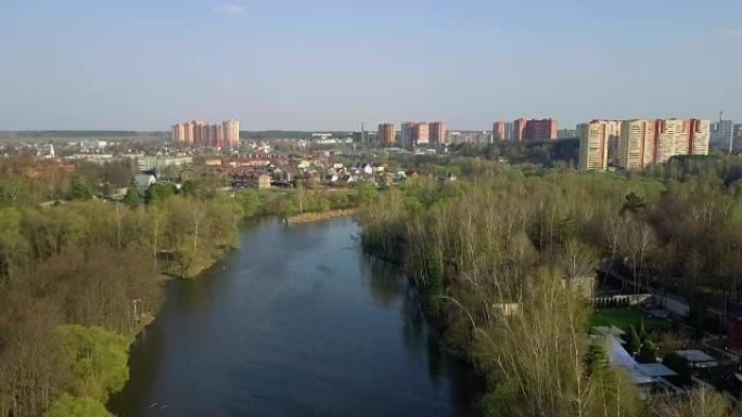 德斯纳河、树木和特罗伊茨克市的鸟瞰图。新莫斯科。摄像机在河上水平缓慢向前移动。春天的时候。晴朗的天气