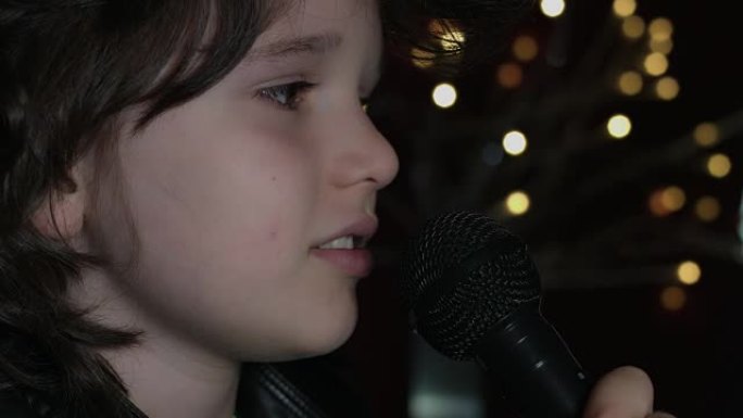 在演播室里用麦克风、特写镜头、发光二极管灯背景唱歌的可爱孩子的4k镜头
