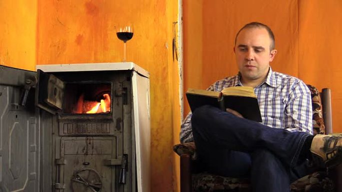 男子看书在火炉旁啜饮葡萄酒