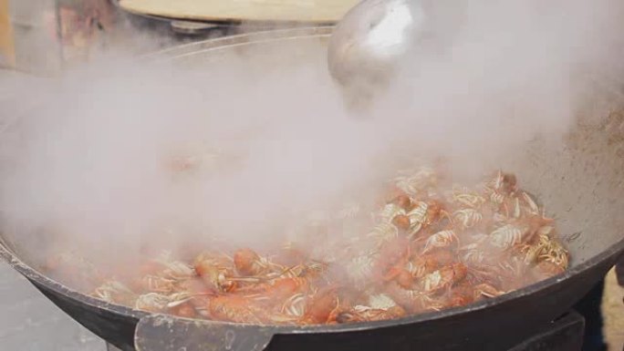 龙虾在大锅里烹饪。街头美食节上的海鲜烹饪过程。在一个大平底锅里煮沸的小龙虾。厨师在大炒锅中准备龙虾，