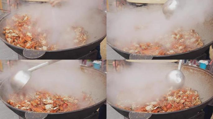 龙虾在大锅里烹饪。街头美食节上的海鲜烹饪过程。在一个大平底锅里煮沸的小龙虾。厨师在大炒锅中准备龙虾，