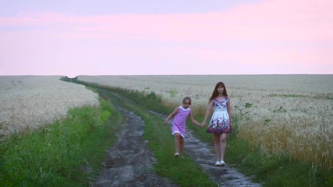 家庭晚上步行的母亲和女儿，在麦田里的道路上，孩子和母亲都在与黑麦穿过田野的道路上。