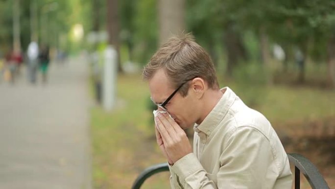 鼻子上拿着手帕的年轻人。一个男人得了重感冒