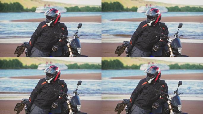 摩托车手在摩托车旁边的河岸上休息