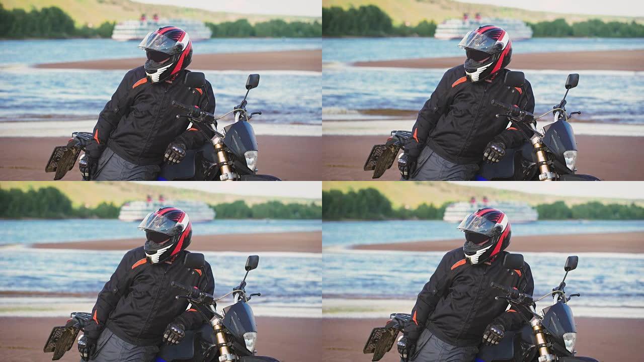 摩托车手在摩托车旁边的河岸上休息