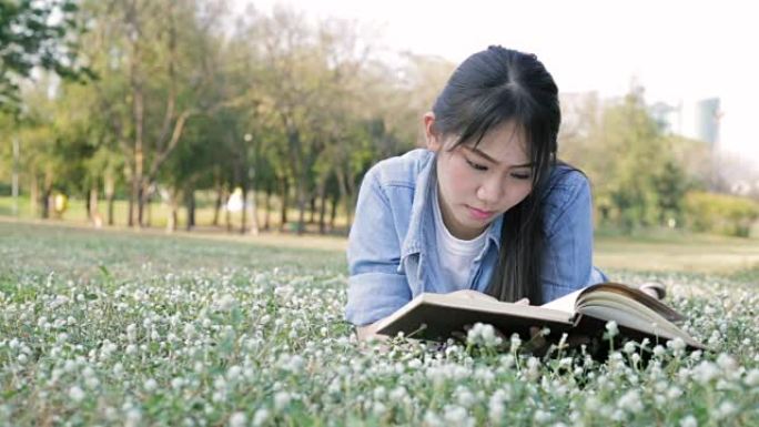 年轻的亚洲女孩在公园看书