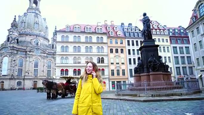 诱人的女孩在电话里聊天，在欧洲城市德累斯顿散步，冬天下午户外美丽的房子和纪念碑的背景下