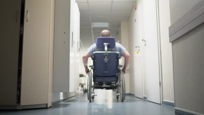 残疾人的后视图将轮椅推下医院走廊