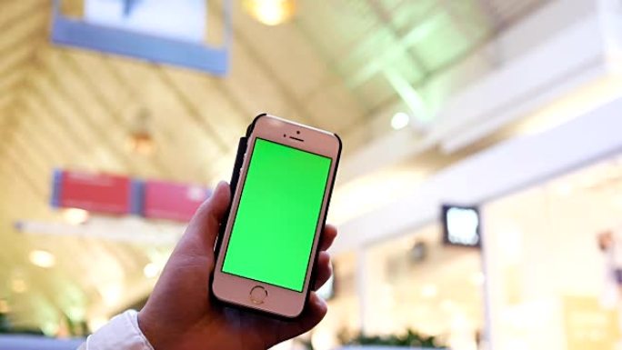 拿着绿屏手机的女人在商场内购物的模糊人的动作