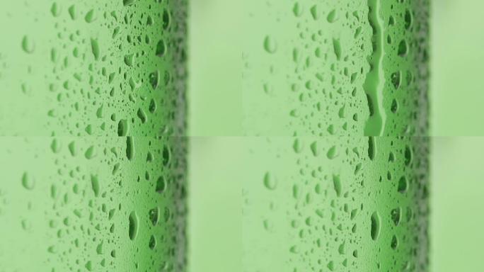 慢动作: 跌落在冰冷的绿色瓶子上滚动-微距拍摄