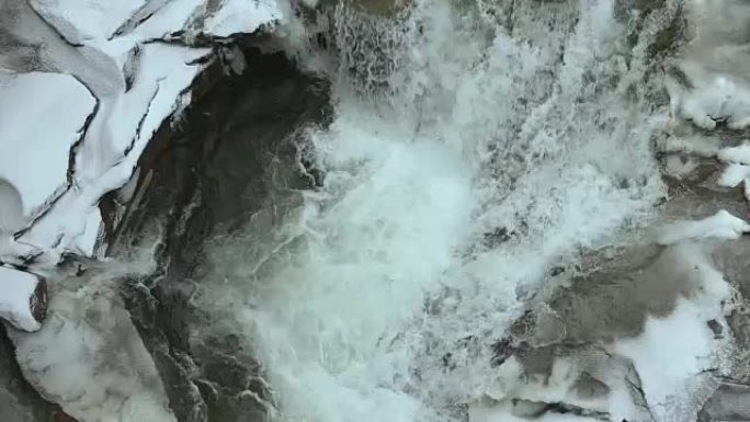 冬季瀑布。水在冰下流动。冰下流动的水