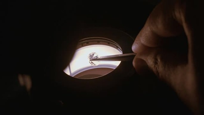 宝石学家在显微镜下检查一颗大而透明的钻石